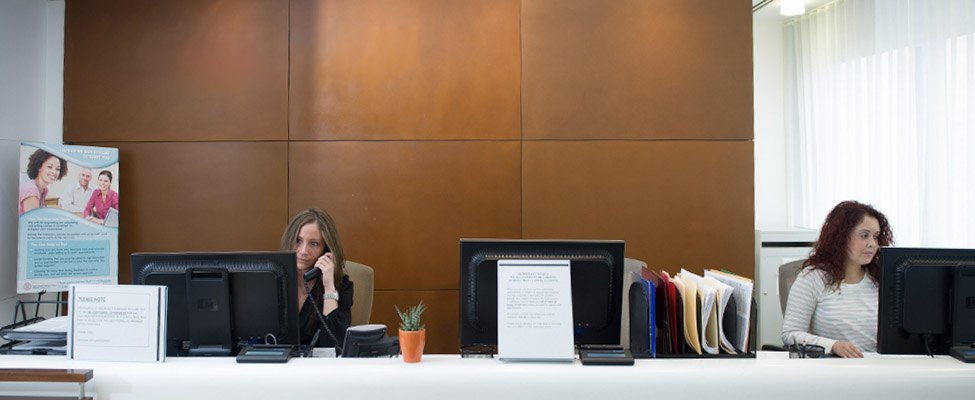 Image of patient care coordinators working at the front desk.