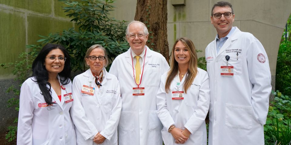 Outdoor group photo of Marfan syndrome and aortopathy providers in front of stone wall and tree